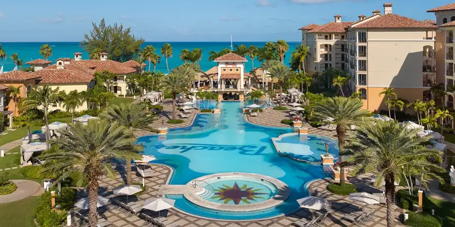 A large central pool with palm trees and the sea nearby, at a Beaches all-inclusive resort