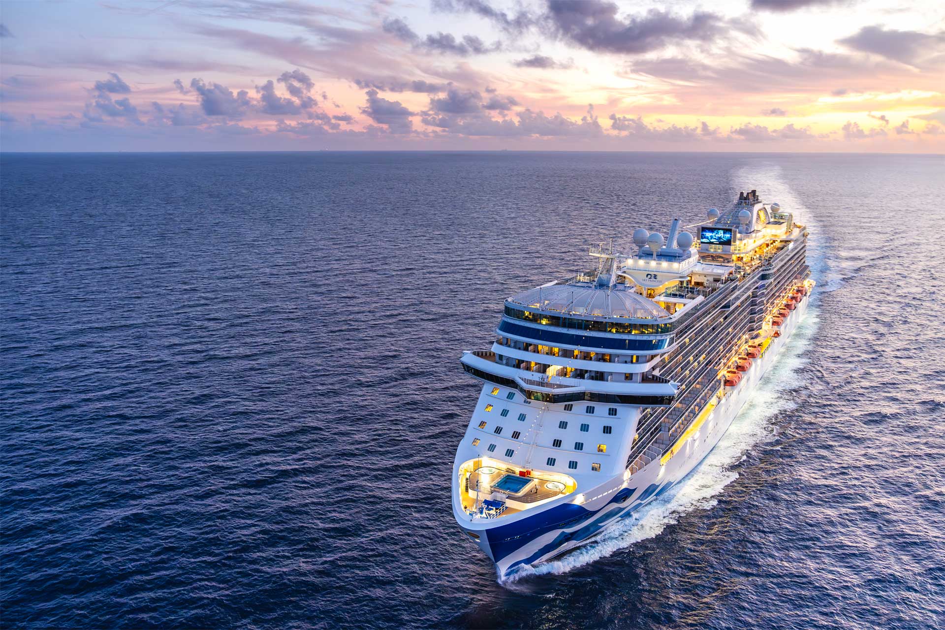 Sky Princess cruise ship sails along, with a colorful sky in the background